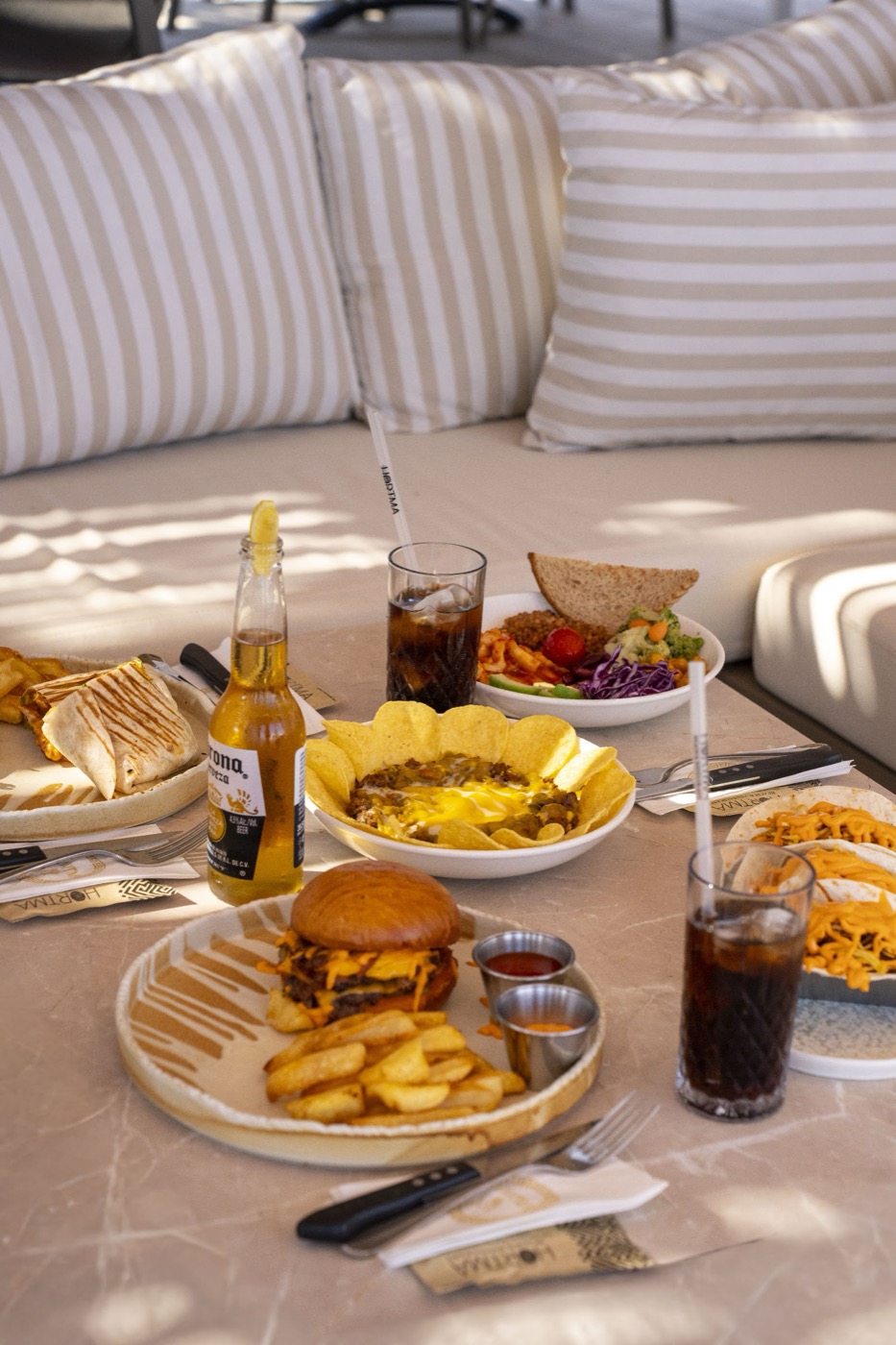 Çizgili minderli köşede burger, patates ve paylaşmalık tabaklar
