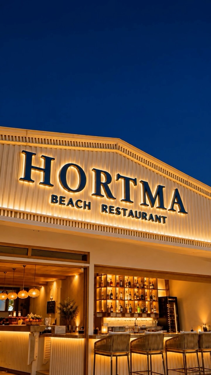 Gece altın ışıklarla aydınlanan Hortma Beach Restaurant cephesi ve bar