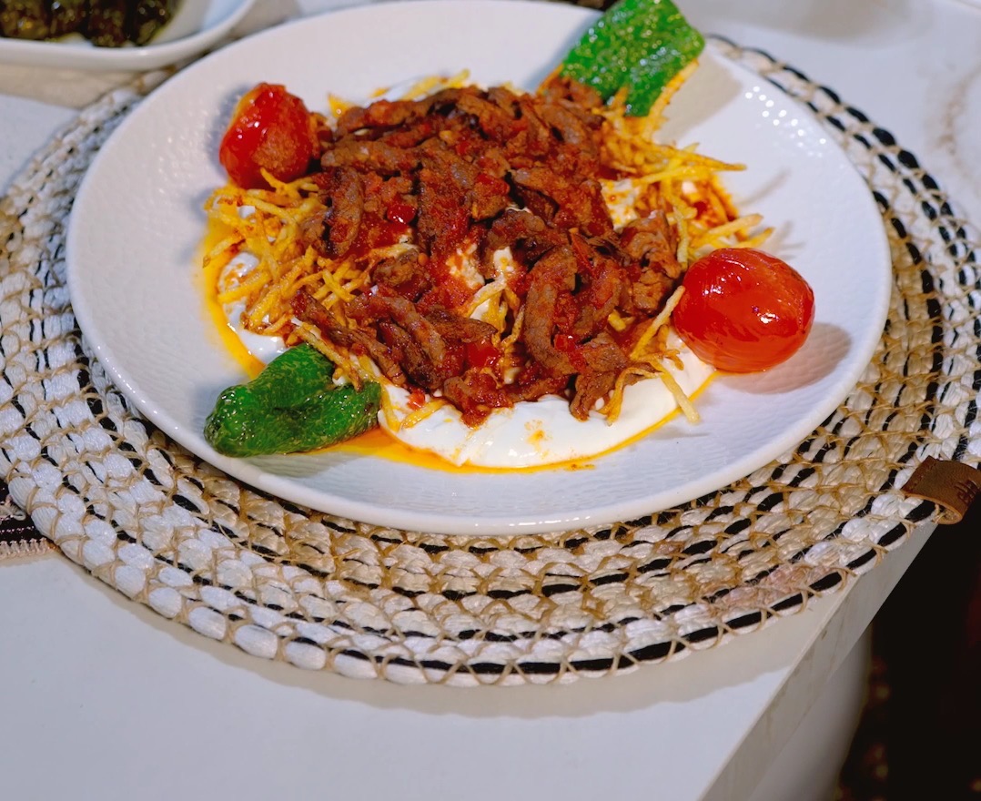 Çıtır patates üzerinde çökertme kebabı, közlenmiş domates ve biberle